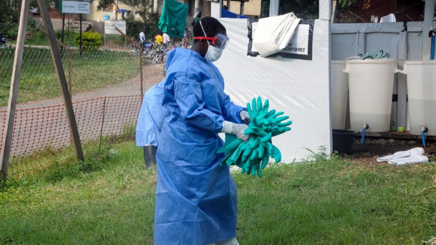 Ein Mitarbeiter in medizinischer Schutzkleidung trägt Schutzhandschuhe in einem Krankenhaus, in dem ein Ebola-Opfer isoliert wur