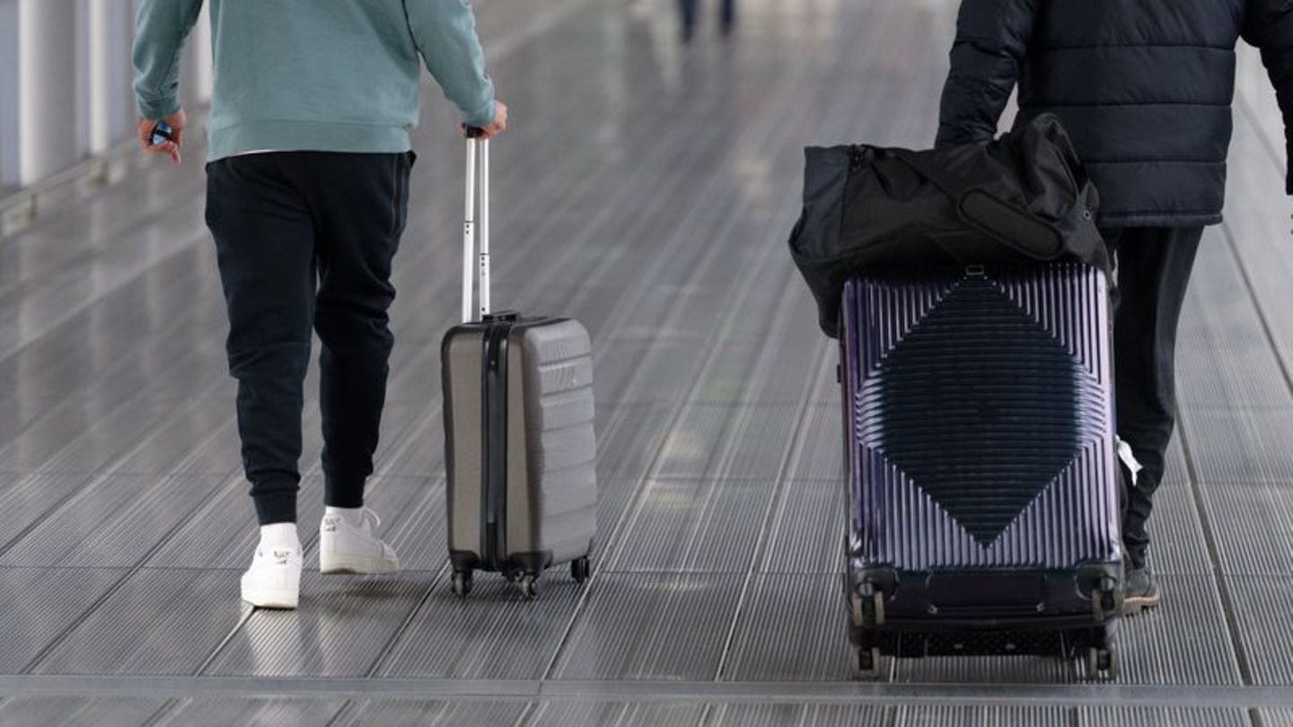 Reisende gehen mit Koffern durch das Terminal 2 des Flughafens Köln Bonn. Foto: Henning Kaiser/dpa